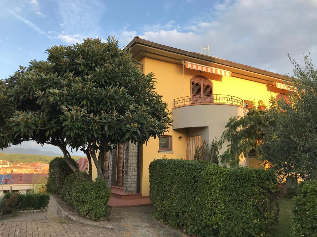 a yellow house with a balcony and trees at Il Nespolo in Cavriglia