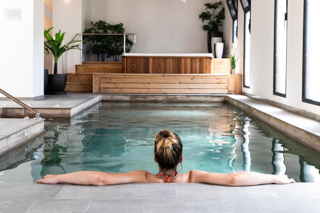 une jeune femme qui se couche dans une piscine dans l'établissement Le Clos Saint Michel Resort & Spa, à Malaucène