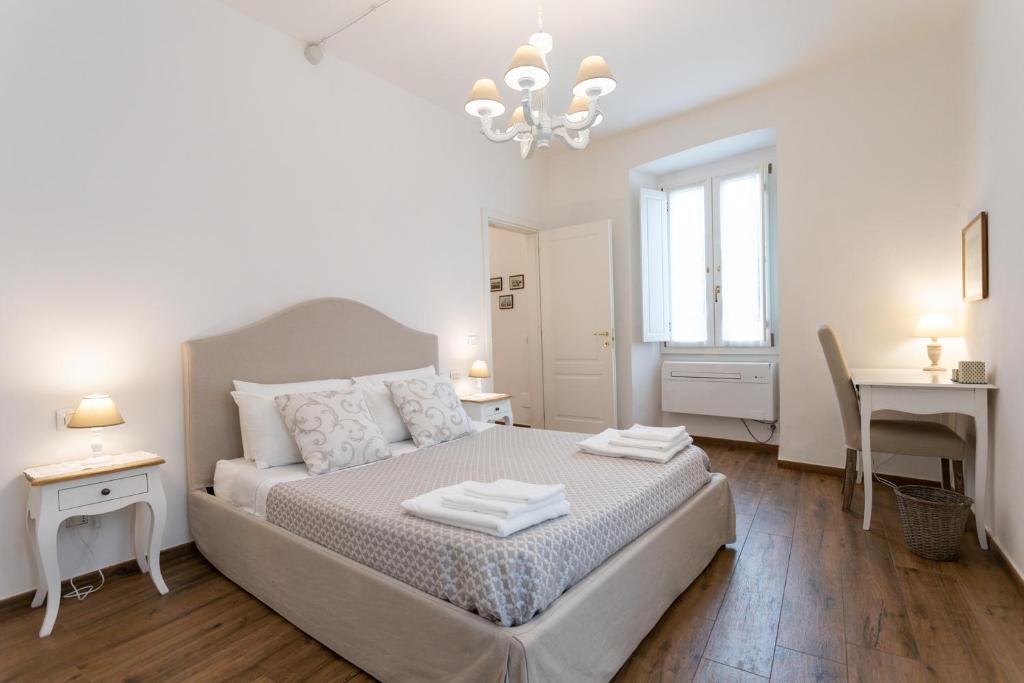 a white bedroom with a bed and a desk at Mercatale Apartment in Prato