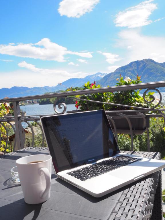 a laptop computer sitting on a table with a cup of coffee at Liza's Suite's - Room's with a View in Sala Comacina