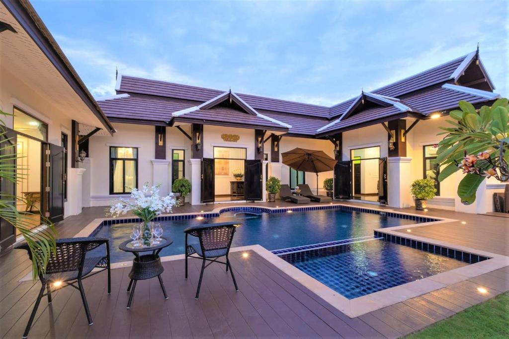 a villa with a swimming pool and a house at Lanna Kamin Pool Villa Airport in Chiang Mai