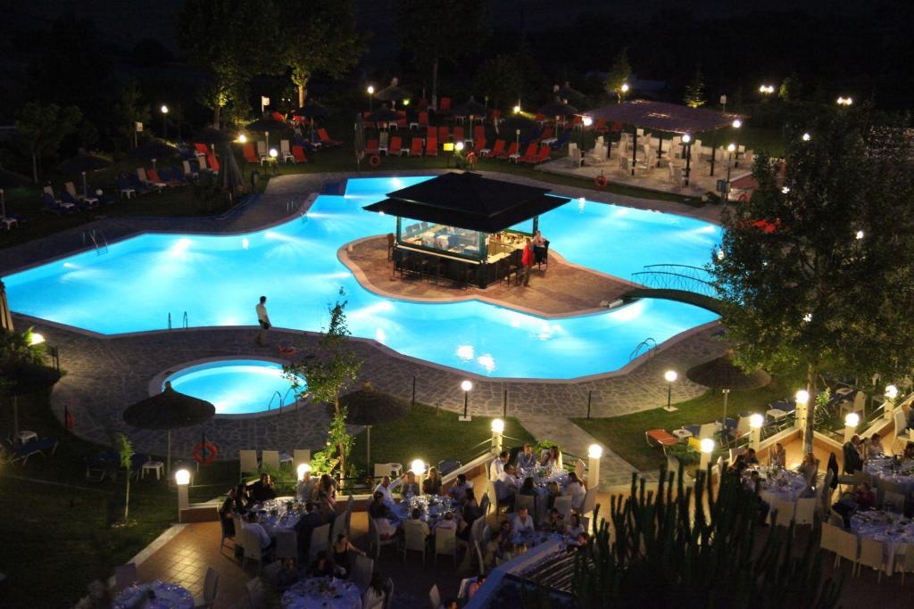 a group of people sitting around a pool at night at Alexander Hotel in Serres