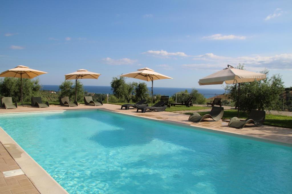 - une piscine avec des chaises longues et des parasols dans l'établissement Agriturismo Vulcano, à Crosia