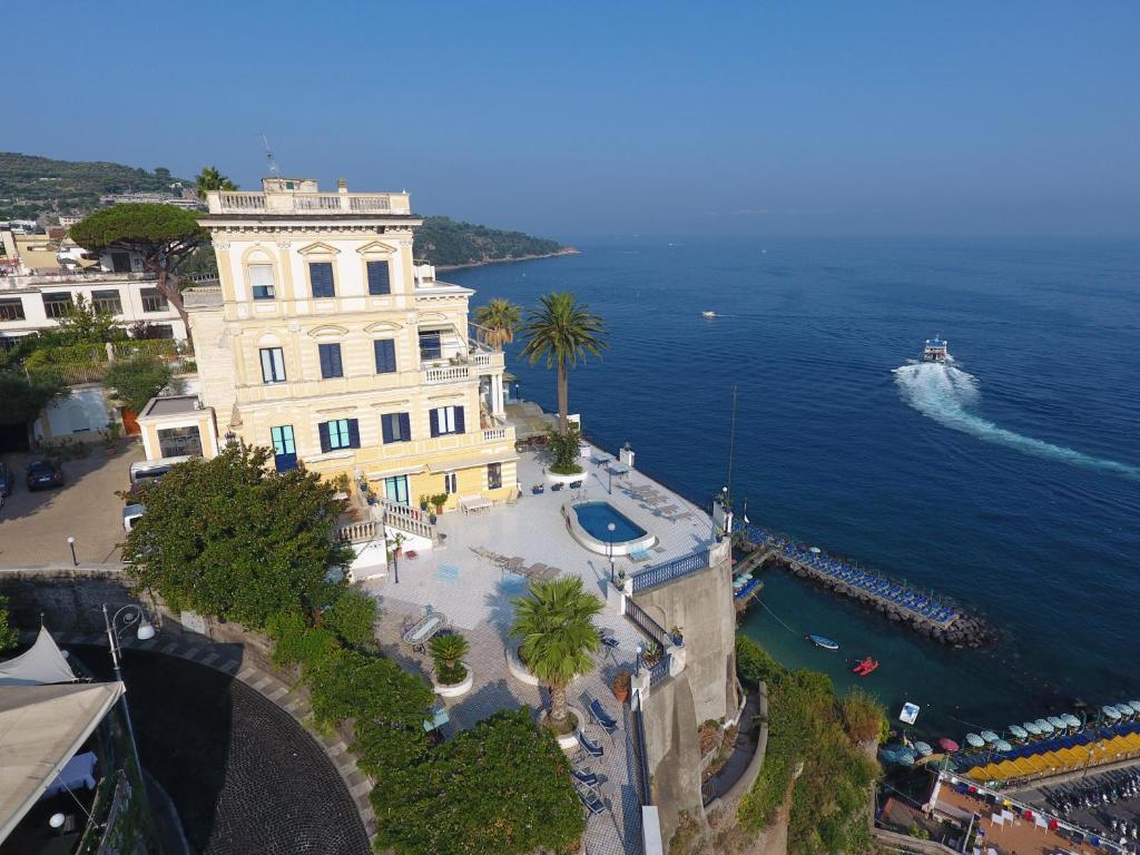 un edificio vicino all'oceano con una barca in acqua di Villa La Terrazza Suites a Sorrento