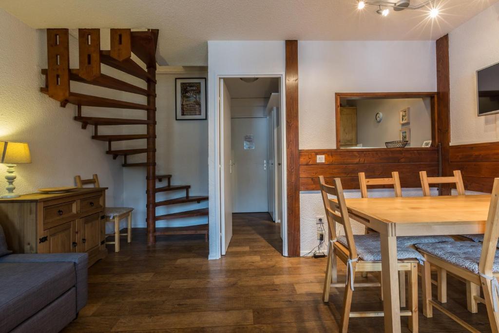 a living room with a dining room table and a staircase at Apartment Jonquille 3 in Chamonix