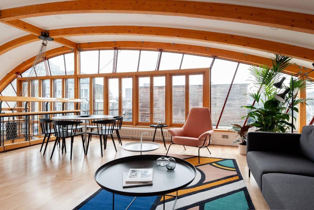 a living room with tables and chairs and windows at Hausd - Piccadilly Circus in London