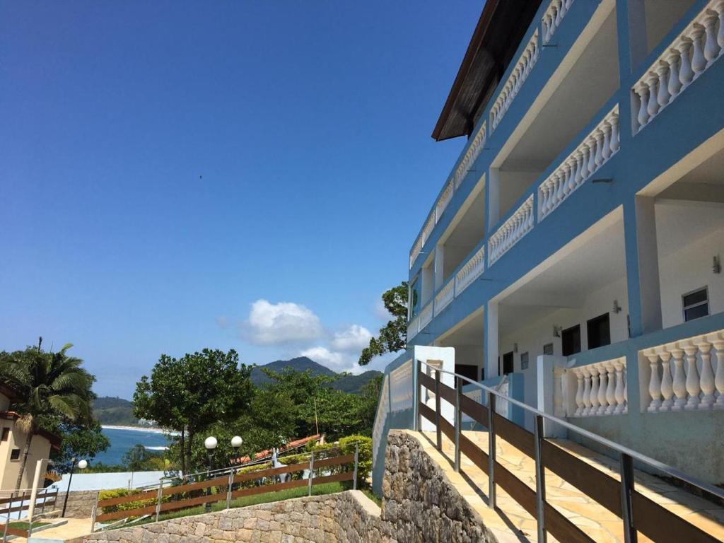 a building with a balcony with a view of the water at Recanto do Teimoso suites in Ubatuba