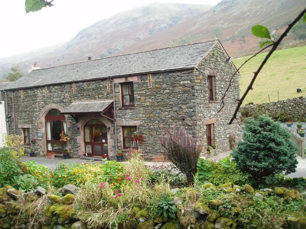 a stone house with mountains in the background at Barn-Gill House in Thirlmere