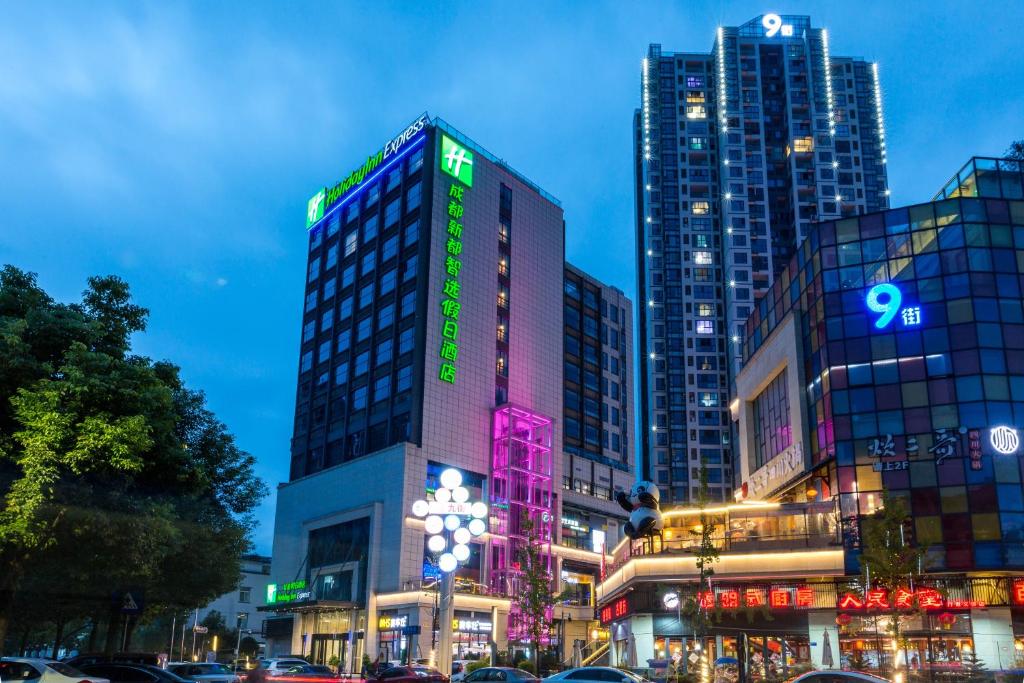 um grupo de edifícios altos em uma cidade à noite em Holiday Inn Express Chengdu Xindu, an IHG Hotel em Chengdu