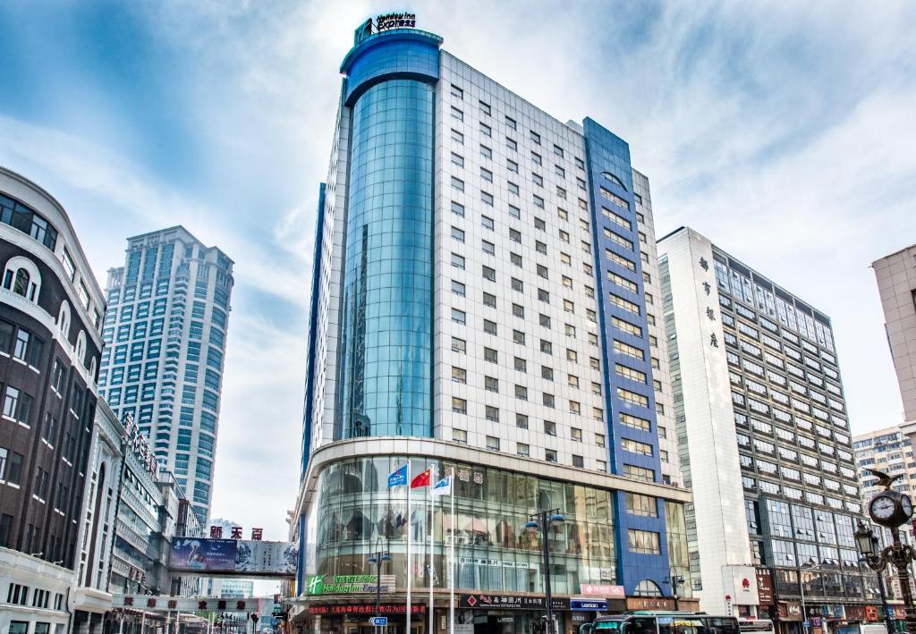 een hoog gebouw met glazen ramen in een stad bij Holiday Inn Express City Centre Dalian, an IHG Hotel in Dalian