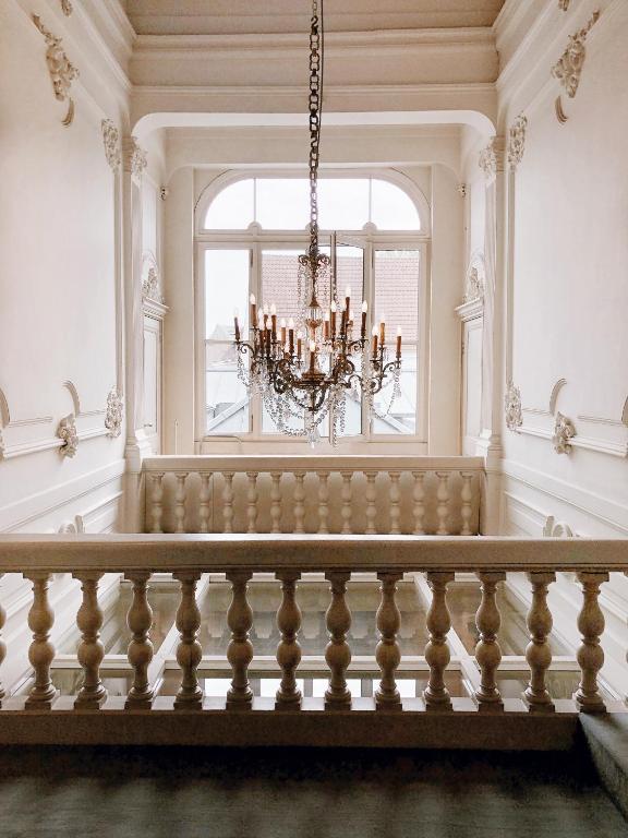 a dining room with a chandelier and a large window at Hotel Van Cleef in Bruges