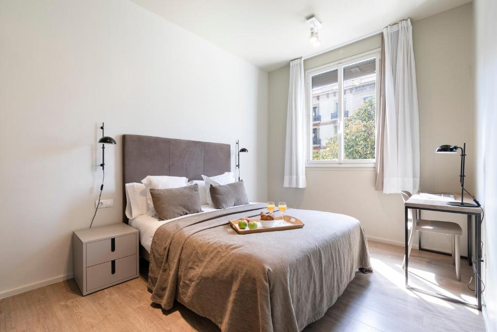 Un dormitorio con una cama con una bandeja de comida. en Aspasios Rambla Catalunya Suites, en Barcelona