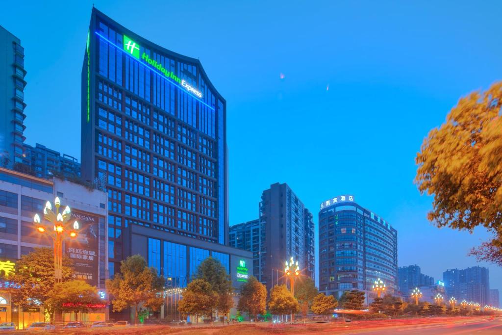 Holiday Inn Express Leshan City Square, an IHG Hotel في ليشان: أفق المدينة في الليل مع المباني الطويلة