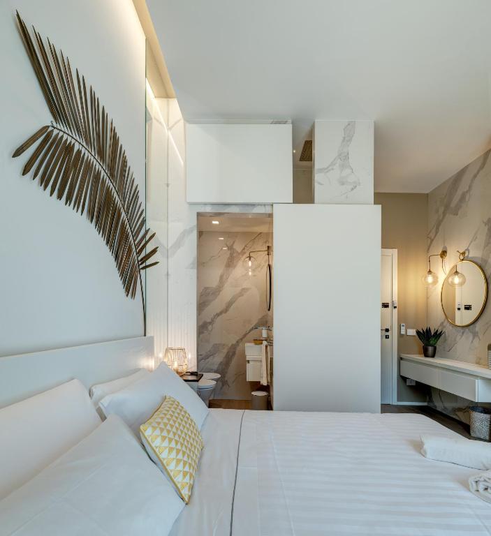 a bedroom with a white bed and a bathroom at Le Palmette Suites in Cagliari