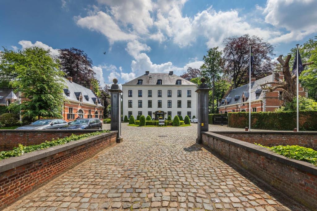 una entrada que conduce a una gran casa blanca en Hotel Kasteel Solhof, en Aartselaar