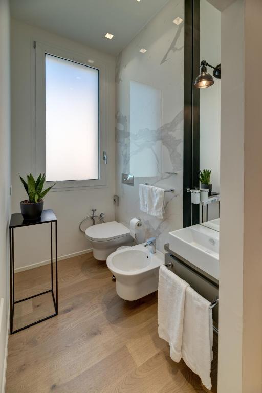 a bathroom with two sinks and a toilet and a mirror at Le Palmette Suites in Cagliari