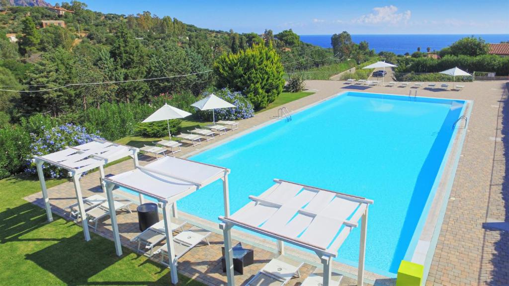 a large swimming pool with lounge chairs at Babai Village Resort in Tertenìa