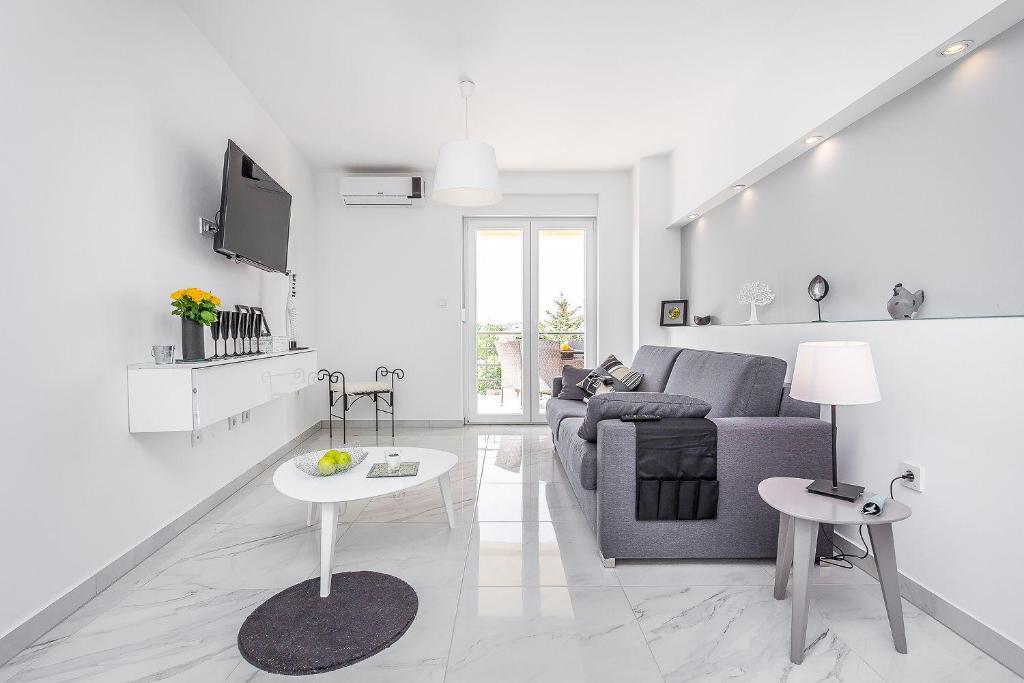 a white living room with a couch and a table at Apartment Pineta in Fondole