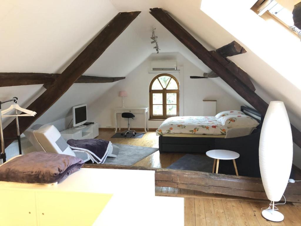 een slaapkamer op zolder met een bed en een bureau bij Ferienwohnung auf denkmalgeschütztem Sturmhof in Grefrath