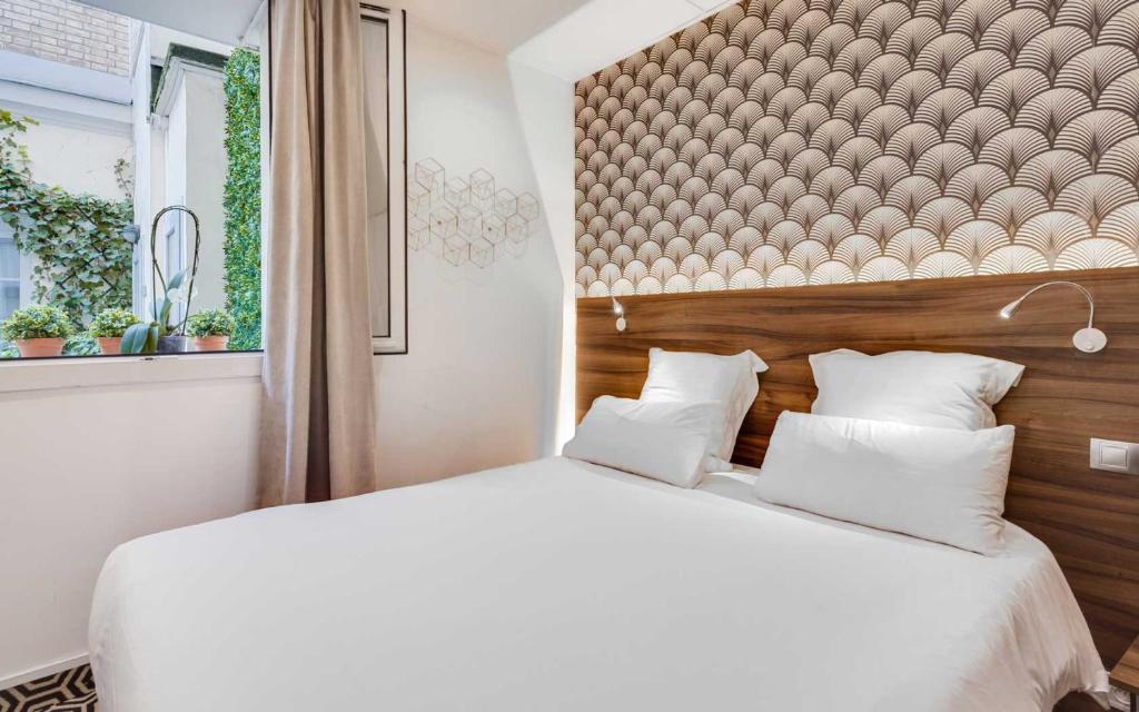 a bedroom with a large white bed with a wooden headboard at Carladez Cambronne in Paris