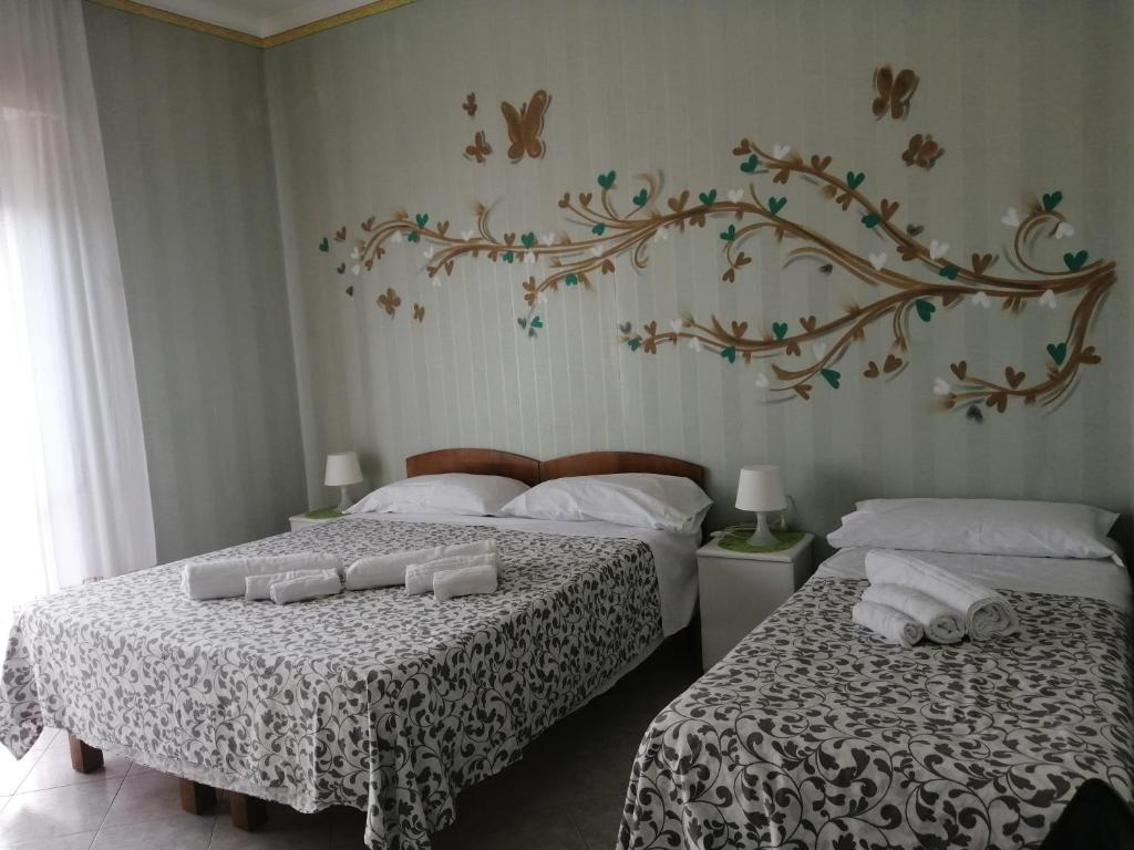 a bedroom with two beds with white sheets and a tree mural at B&B A Casa Dei Nonni in Capua