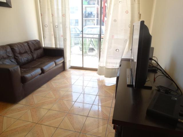 a living room with a couch and a television at D14-9 Arriendo diario a pasos de la playa Arica in Arica