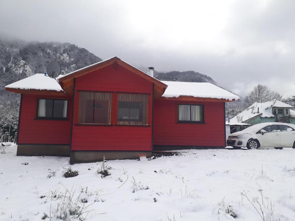a red house with snow on top of it at Cabaña San Pedro in Malalcahuello