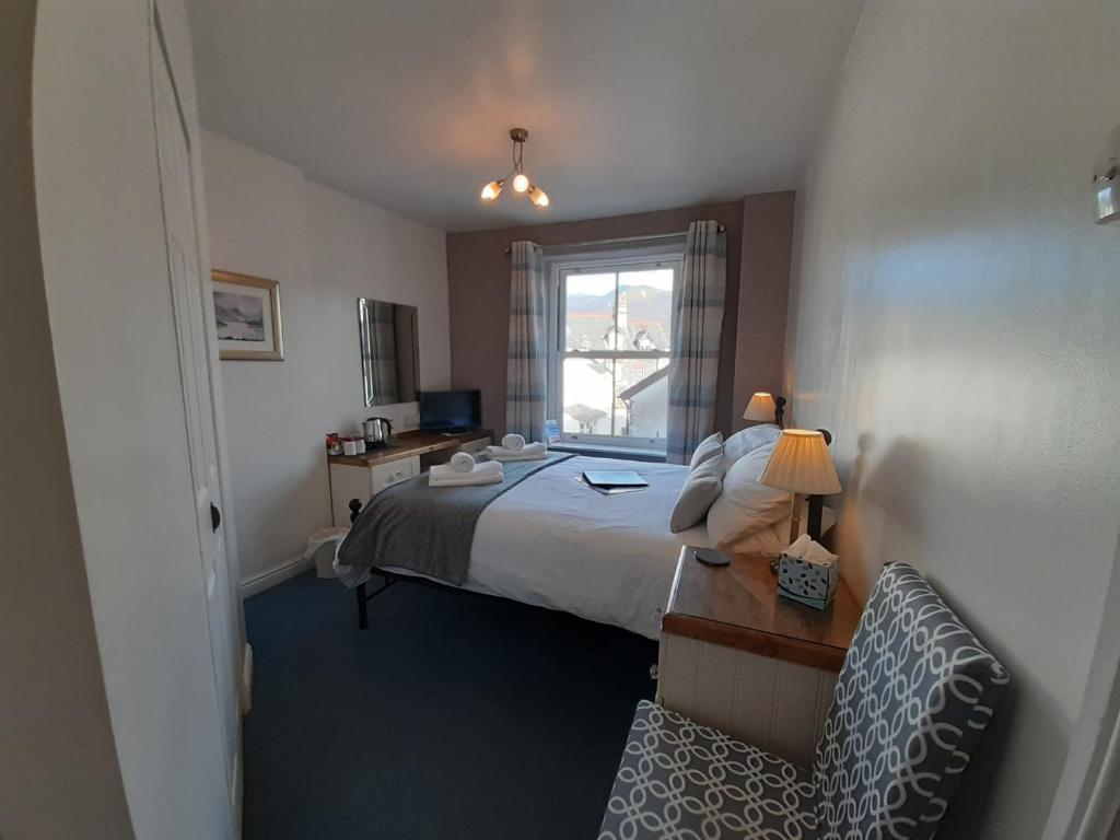 Schlafzimmer mit einem Bett, einem Schreibtisch und einem Fenster in der Unterkunft Harvington House in Keswick