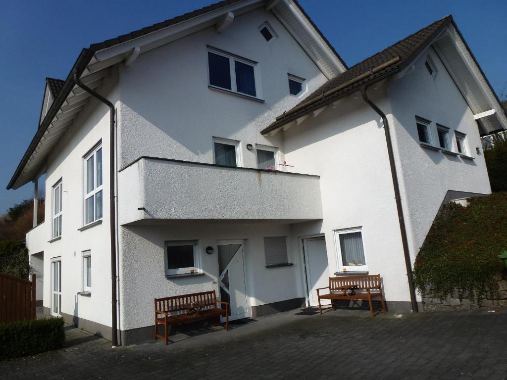 a white building with two benches in front of it at Ferienwohnung Erpel in Olpe