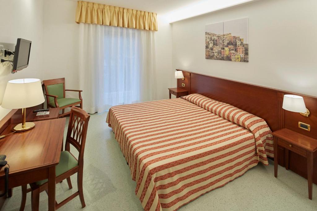 a hotel room with two beds and a desk at Hotel Villa Adriana in Monterosso al Mare