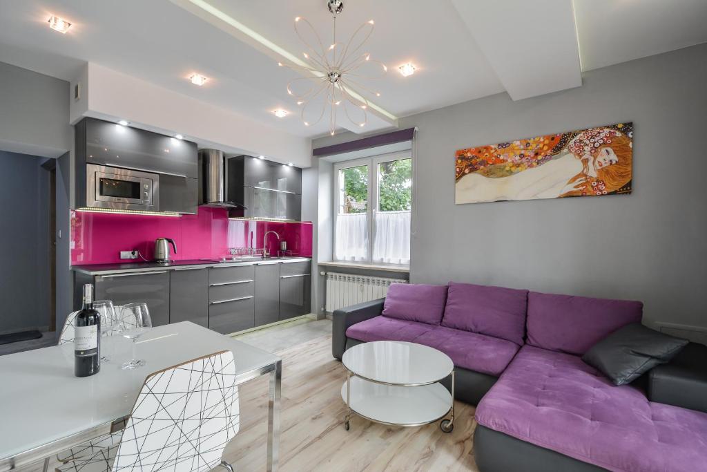 a living room with a purple couch and a kitchen at Apartament Hrabiego Centrum in Zakopane