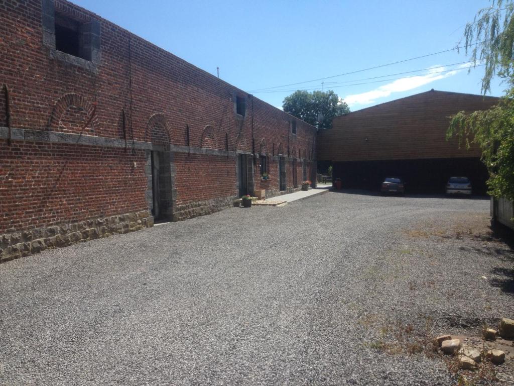 um parque de estacionamento vazio ao lado de um edifício de tijolos em La gaîté de louvignies em Louvignies-Quesnoy