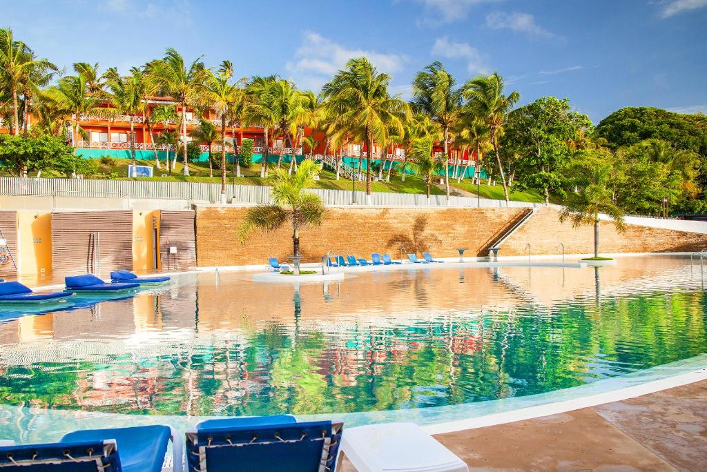 una piscina con sillas azules y palmeras en Sol Caribe Campo All Inclusive, en San Andrés