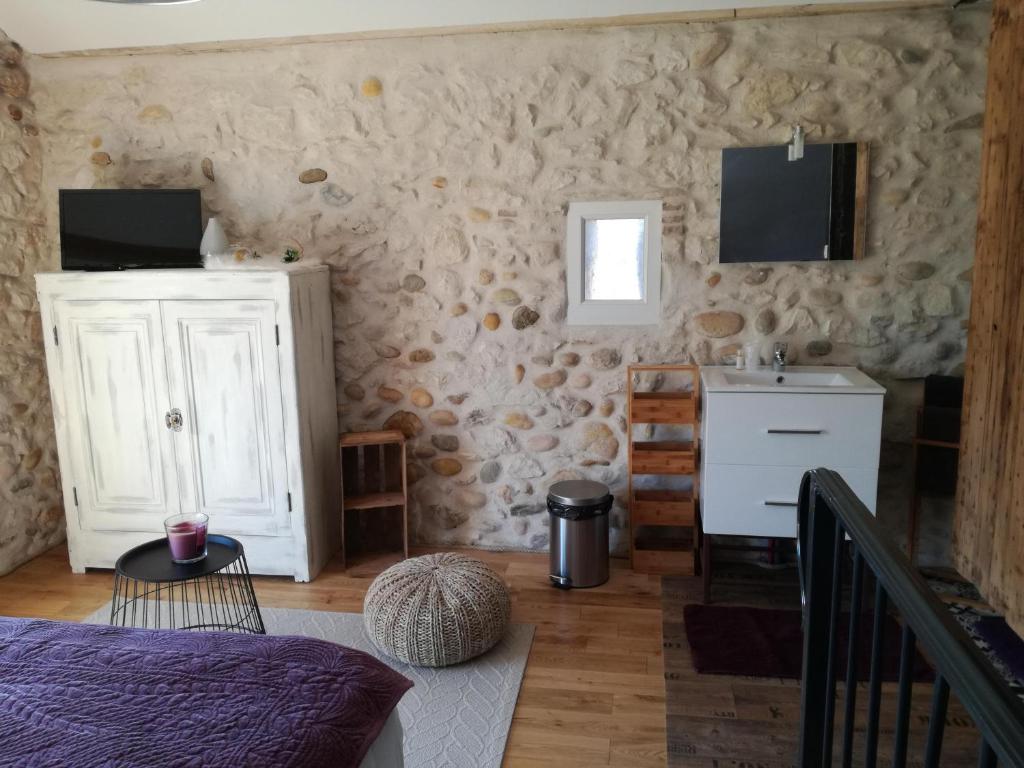 a bedroom with a stone wall with a bed and a sink at La Chabottine Vercors in Saint-Just-de-Claix