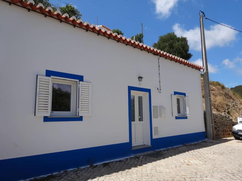 a white and blue building with a door and windows at Casa da Ponte de Pedra in Aljezur