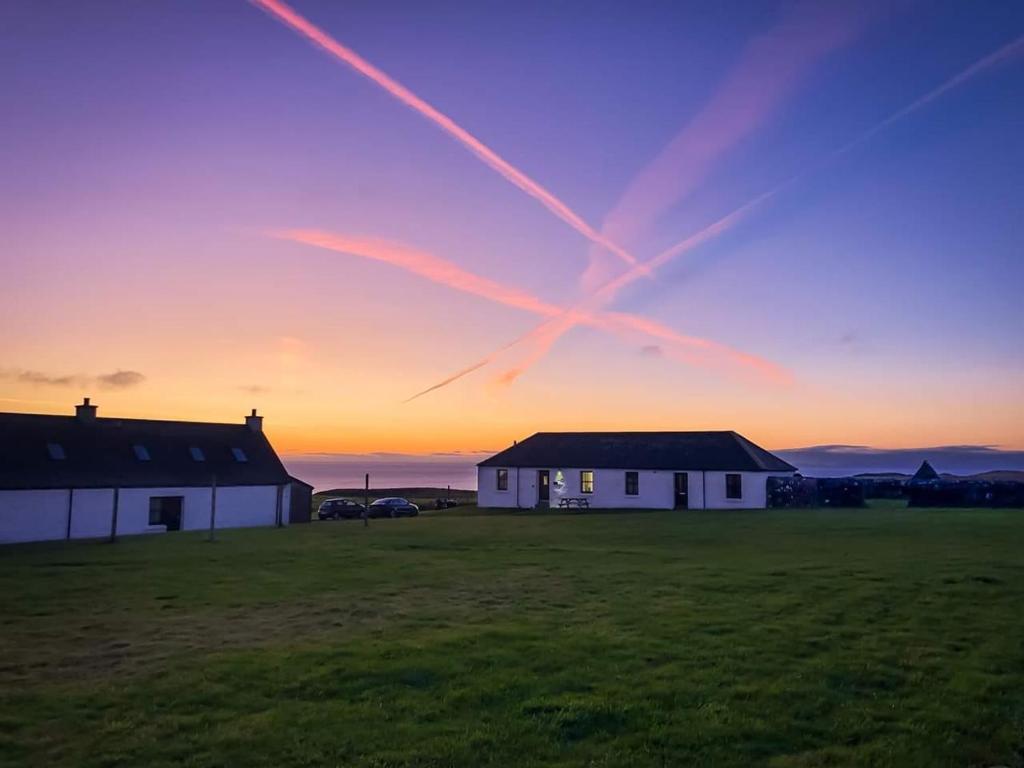 a house in a field with the sunset in the background at Monkstadt No 6 -Jessie's Hideaway in Portree