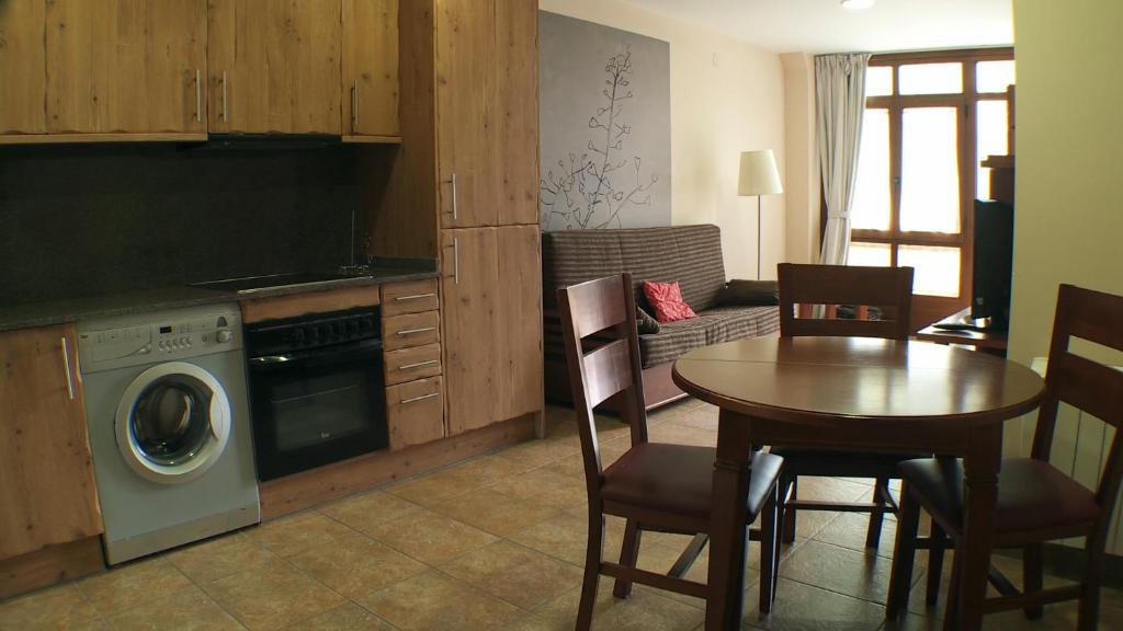 a living room with a table and a kitchen with a washing machine at Anticforn in Bohí