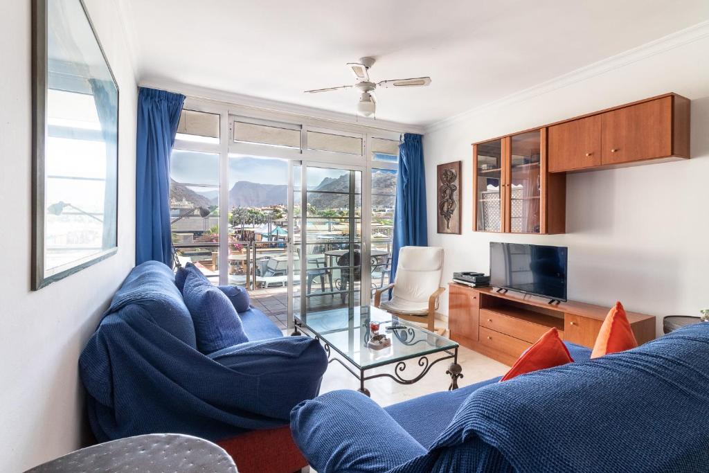 uma sala de estar com sofás azuis e uma televisão em Flatguest Mogan + Beach + 2Bdr + Terrace em Mogán