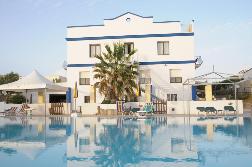 un hotel con piscina di fronte a un edificio di Hotel Stella Del Sud a Calasetta