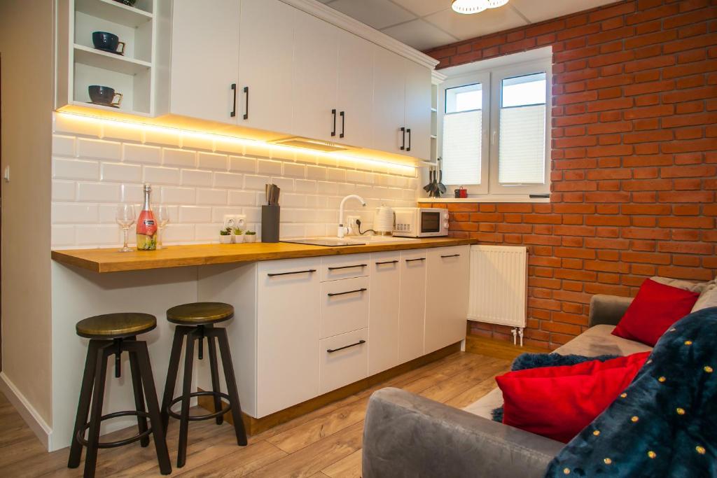 a kitchen with white cabinets and a brick wall at Main Street Chłodna Apartment in Suwałki