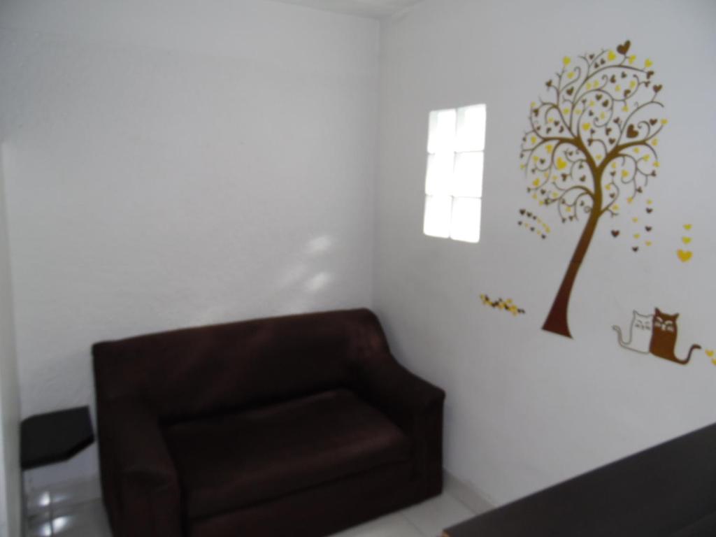 a chair in a room with a tree on the wall at Amoblados Medellín Laureles in Medellín