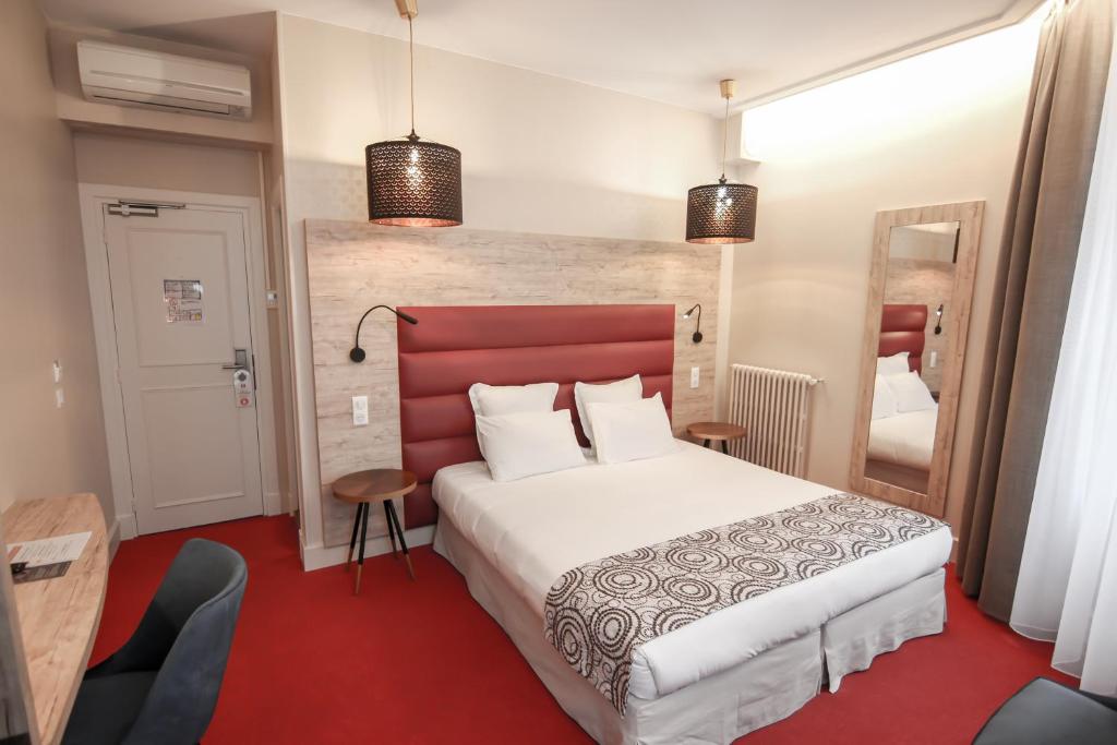 a bedroom with a large white bed with a red headboard at Hôtel Montaigne in Sarlat-la-Canéda