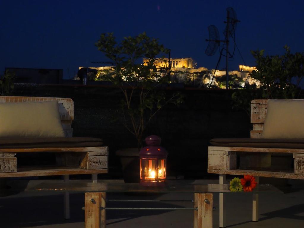 a lantern sitting between two benches at night at Psirri Artistic Rooftop Apartment with Acropolis View in Athens