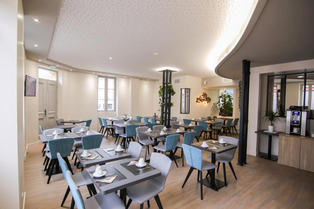a dining room with tables and blue chairs at Hôtel Montaigne in Sarlat-la-Canéda