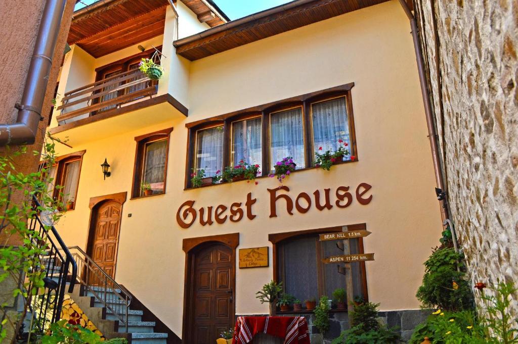 a guest house with a guest house sign on the side of a building at Palyongov Guest House in Chepelare