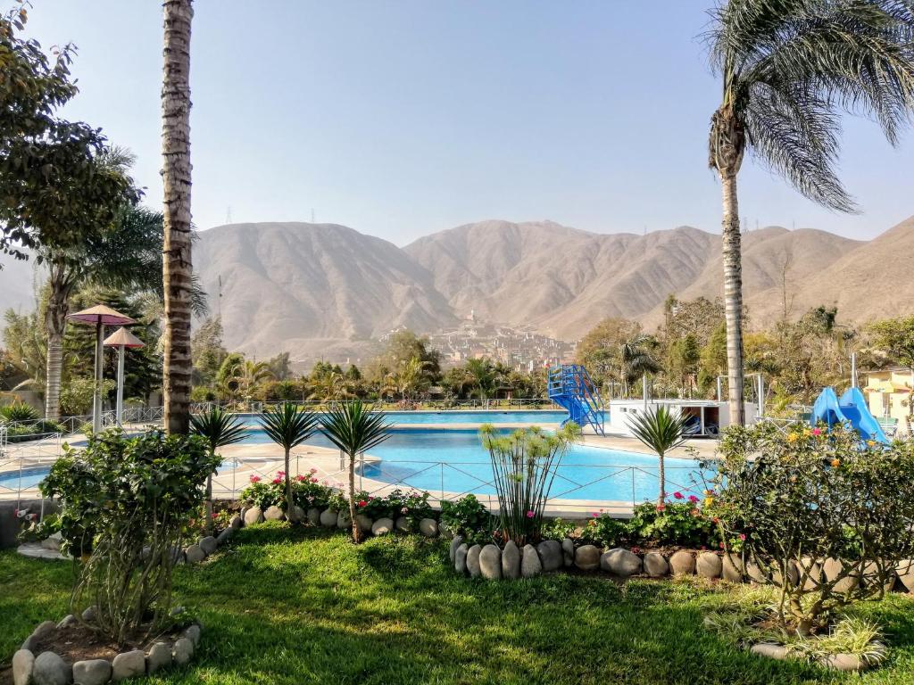une piscine avec des palmiers et des montagnes en arrière-plan dans l'établissement Mi Pequeño Club (Country Club), à Lima