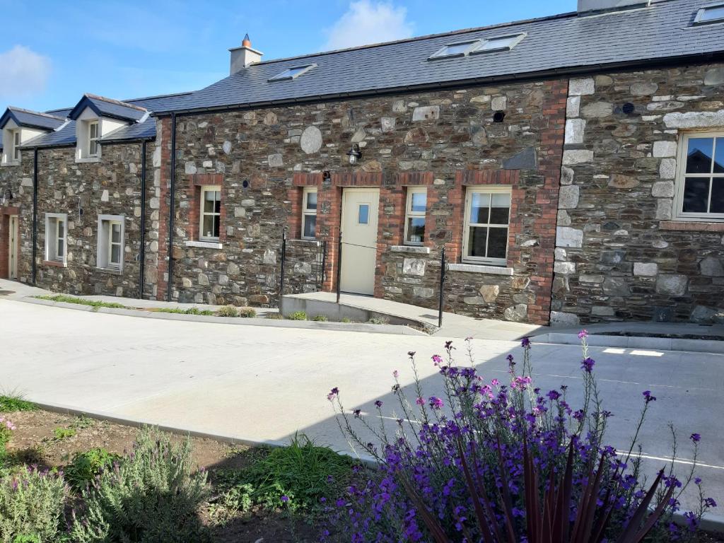 a stone building with a driveway and purple flowers at Holywood House No 2 in Hollywood