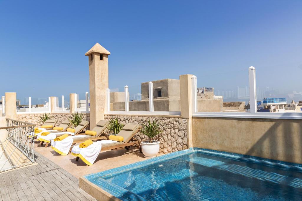 uma piscina no telhado de um edifício com espreguiçadeiras em Suite Azur Hotel em Essaouira