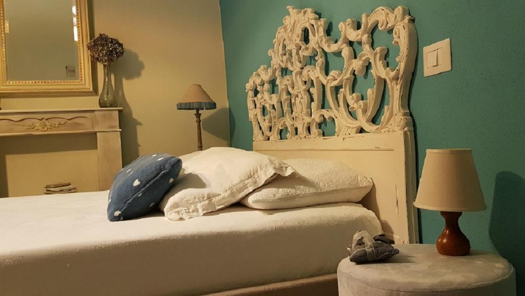 Schlafzimmer mit einem Bett mit einem weißen Kopfteil und einem Spiegel in der Unterkunft Cortile Gancia - Sweet House in Narzole