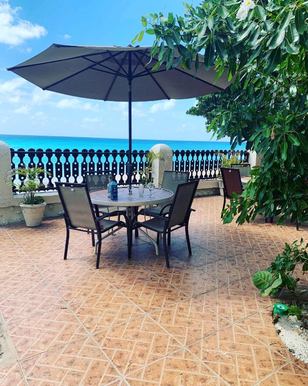 a table with chairs and an umbrella on a patio at Beach Vue Barbados in Bridgetown